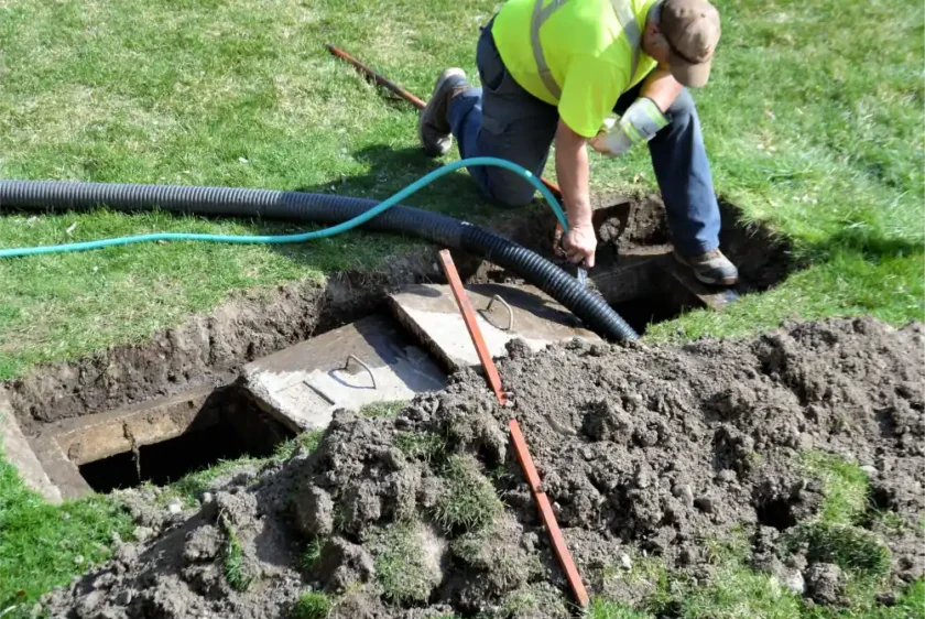 Technician performing septic tank pumping service for residential property