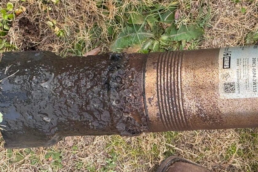 Septic pump lying on the grass with its intake end completely caked in solids
