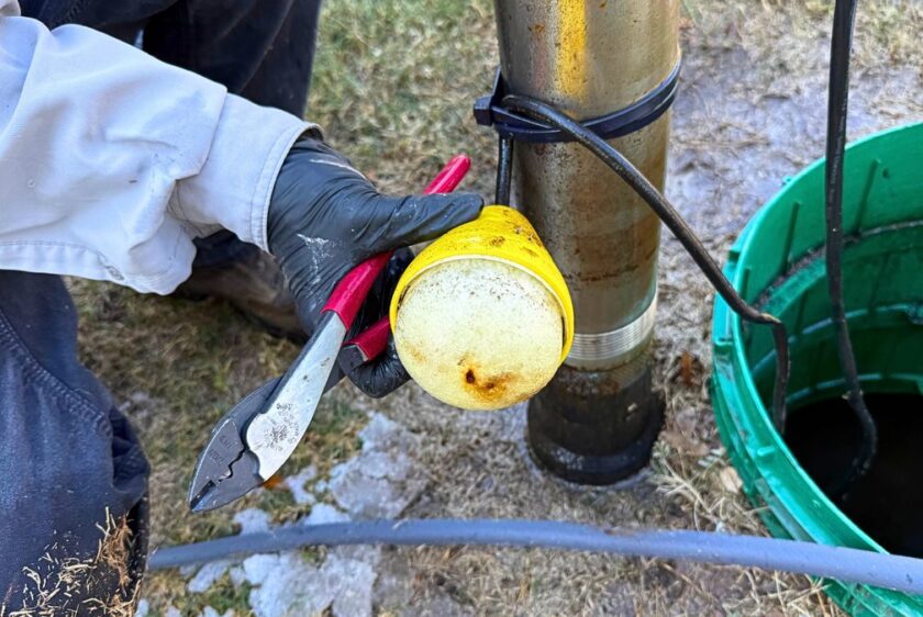 Technician inspecting a float switch removed from a septic pump tank