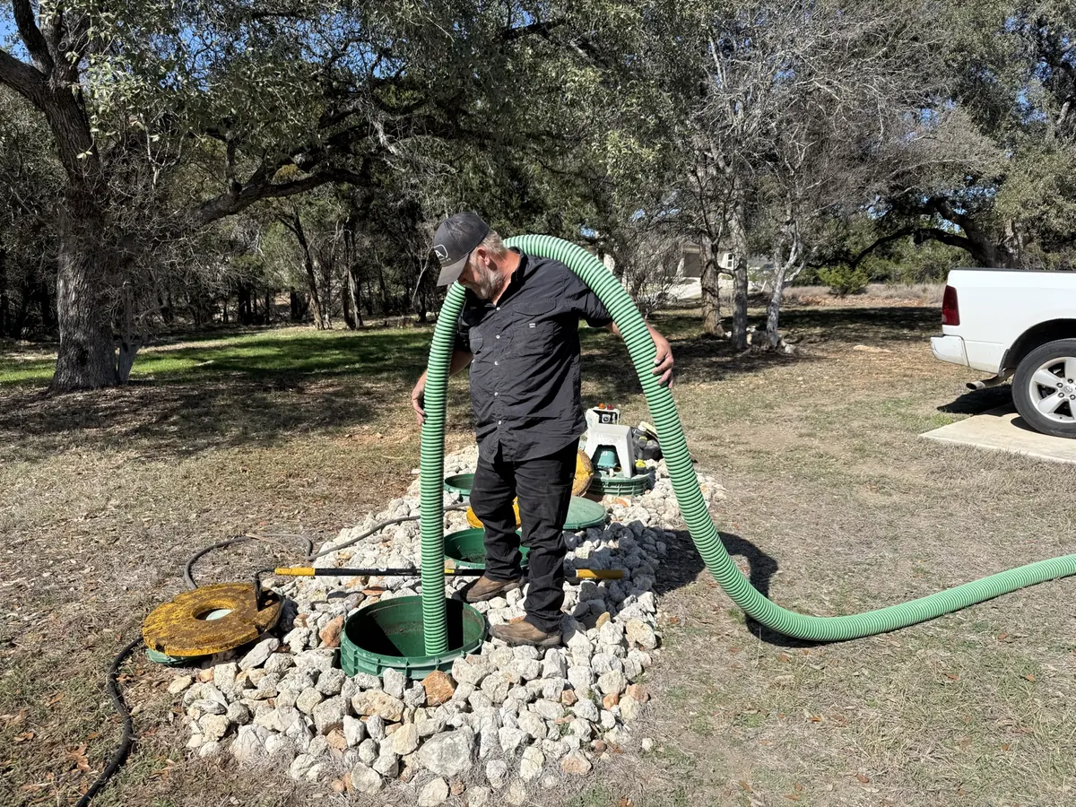 Luna technician running a suction hose into a septic tank during a pump out